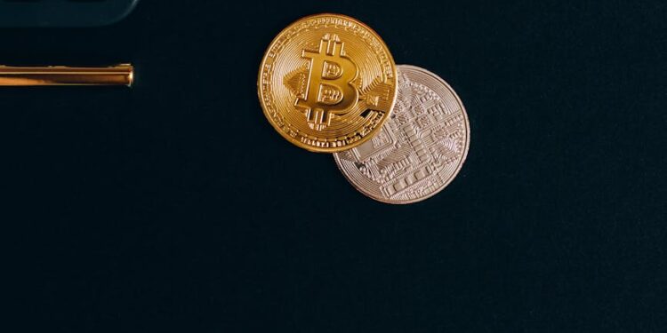 A stack of coins with Bitcoin and Ethereum logos beside a calculator and financial documents.