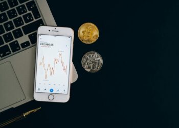 Oil barrels and Bitcoin coins with rising and falling graphs in the background.