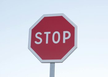 Dark screen displaying cryptocurrency symbols with a red warning sign indicating regulation.