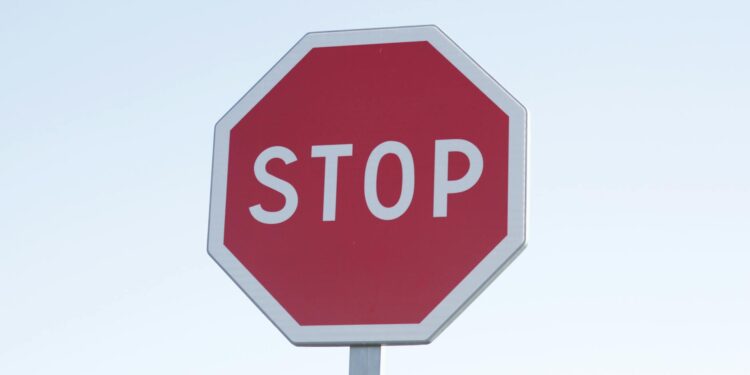 Dark screen displaying cryptocurrency symbols with a red warning sign indicating regulation.