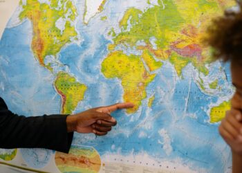 Falling Bitcoin chart juxtaposed with world map highlighting geopolitical tensions.