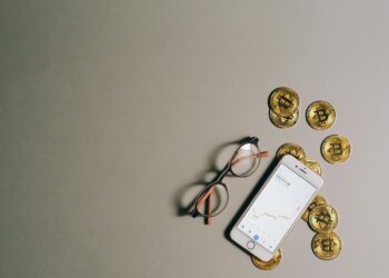 Bitcoin coins stacked with a fluctuating stock market graph in the background.