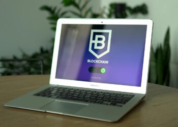 A developer analyzing code on a laptop with blockchain graphics in the background.