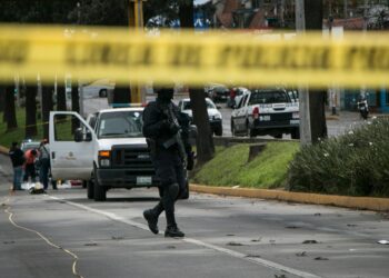Police at a crime scene near a school, investigating a recent shooting incident.