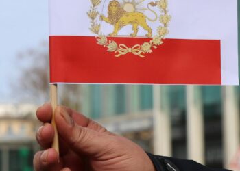 Iranian officials discussing cryptocurrency regulations with a backdrop of the Revolutionary Guards emblem.