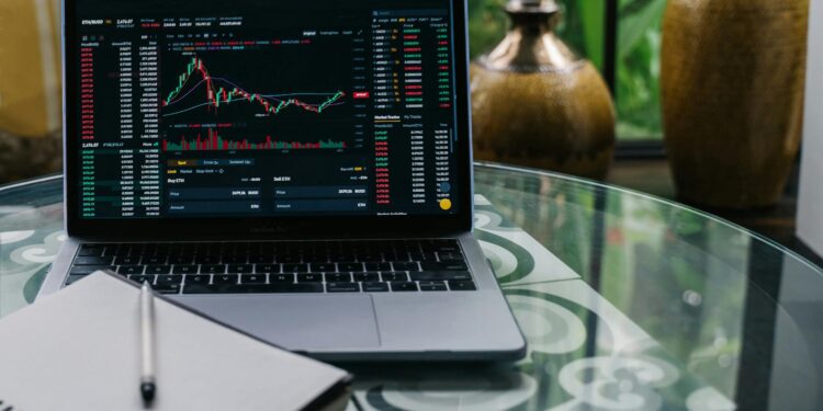 A person reviewing DeFi platforms on a laptop with financial charts and crypto symbols visible.