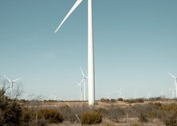 Wind turbines surround a sprawling data center building in Texas, highlighting renewable energy use.
