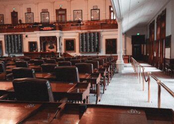 Legislators discussing AI surveillance warrant regulations in a government meeting room.