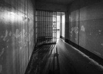 Crowded detention center with somber faces reflecting harsh conditions and reported violations.