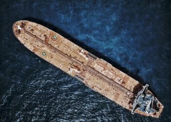 Oil tankers navigate the Strait of Hormuz with cryptocurrency toll signs on the water.