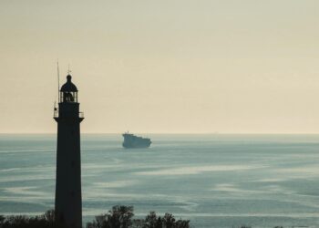 A cargo ship navigates the Strait of Hormuz, symbolizing maritime finance vulnerabilities.