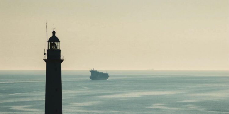 A cargo ship navigates the Strait of Hormuz, symbolizing maritime finance vulnerabilities.