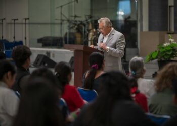 Jon Husted speaking at a podium with a Sentinel Action Fund banner in the background.
