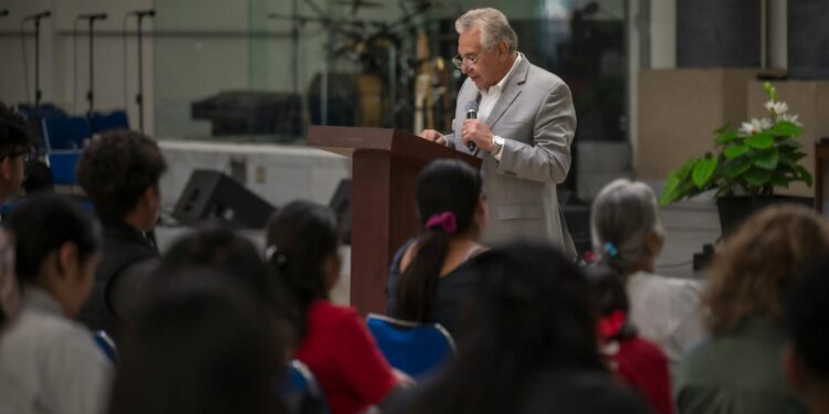 Jon Husted speaking at a podium with a Sentinel Action Fund banner in the background.