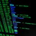 Fragments of code on a screen with a cryptocurrency wallet and a news headline about the hack.