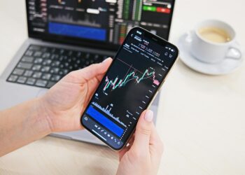Trader analyzing crypto charts on a smartphone with a Telegram app interface displayed.