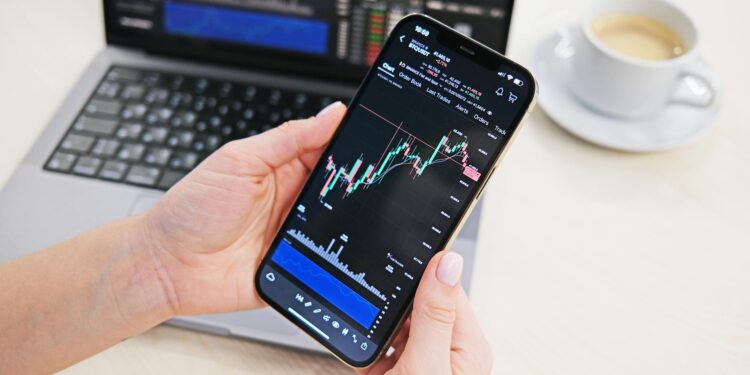 Trader analyzing crypto charts on a smartphone with a Telegram app interface displayed.