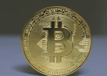 A Bitcoin coin stands strong against oil barrels, symbolizing market resilience amidst Iran tensions.