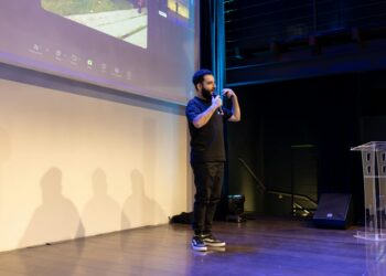 Sam Bankman-Fried speaking at a conference with FTX branding in the background.