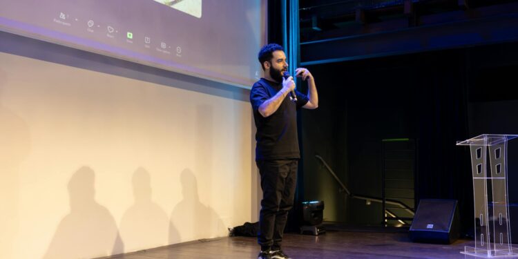 Justin Sun speaking at a conference with blockchain graphics in the background.