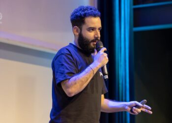 Dan Finlay speaking at a crypto conference, gesturing passionately to the audience.