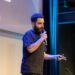 Dan Finlay speaking at a crypto conference, gesturing passionately to the audience.