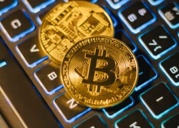 Golden Bitcoin coins stacked on a computer keyboard, symbolizing crypto finance and security.