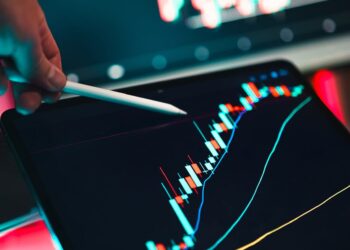 A person analyzing stock market data on a computer screen with crypto and oil price graphs.