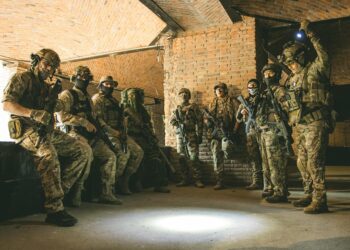 Special Forces operative entering a courtroom, surrounded by media and legal personnel.