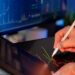 A financial analyst examining Bitcoin trends with declining charts in the background.