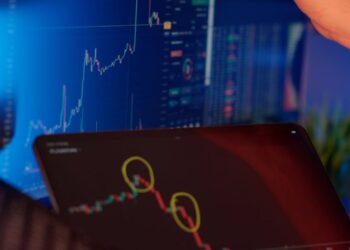 A business professional reviews financial graphs on a laptop, featuring crypto and fiat integrations.