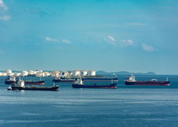 Oil tanker in port with Bitcoin symbol overlay, highlighting crypto use amid sanctions.