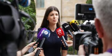 Lori Chavez-DeRemer at a press conference, looking serious, surrounded by reporters.