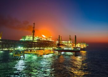 Oil rigs at sea with rising graphs, reflecting market volatility due to naval tensions.