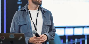 Justin Sun speaking at a cryptocurrency conference, with attendees and media in the background.