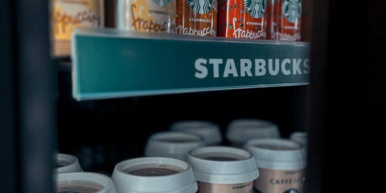 Barista using a tablet to suggest personalized drinks with LattAI app at a Starbucks store.