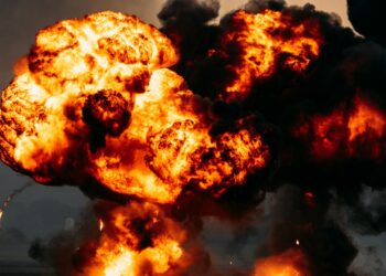 Flames erupt from a damaged oil pipeline, with smoke rising against a darkened sky.