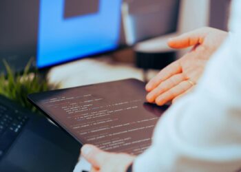 A developer uses a no-code AI app builder on a laptop in a modern workspace.