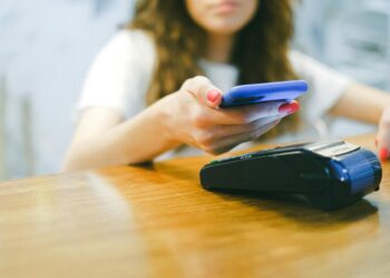 A person using a smartphone to make a crypto payment at a restaurant.