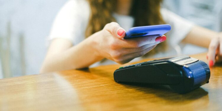 A person using a smartphone to make a crypto payment at a restaurant.