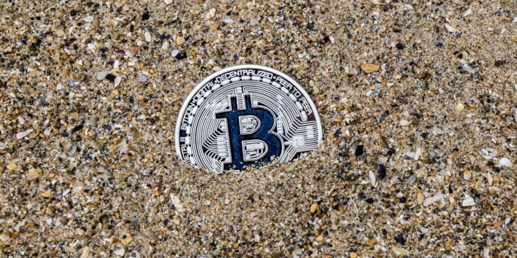 A stranded ship in the Strait of Hormuz with digital currency symbols overlayed.