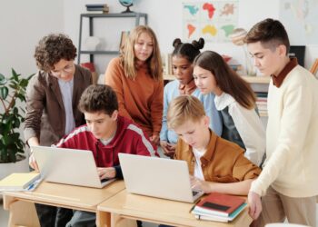 Students in a classroom setting engage with laptops during an AI training session.