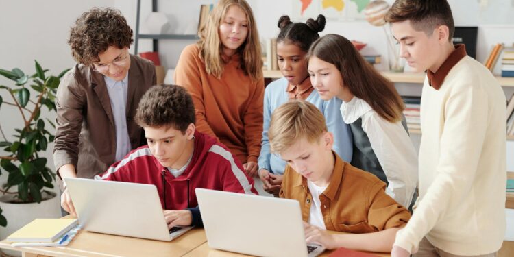 Students in a classroom setting engage with laptops during an AI training session.