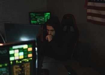 A hacker at a computer, with cryptocurrency symbols and a Russian flag in the background.
