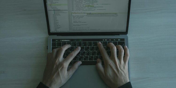 A cybersecurity expert analyzes code on a laptop, revealing vulnerabilities in software.