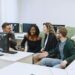 Diverse group of apprentices engage with computers in a modern training facility.