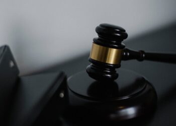 A gavel rests on a document with financial regulations and cryptocurrency symbols.