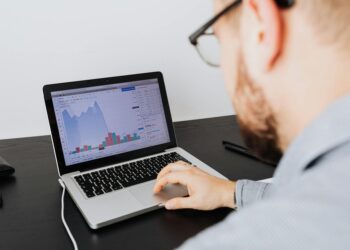 A person analyzing cryptocurrency data on a laptop screen with charts and graphs displayed.