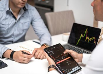 Two financial professionals discuss crypto technology with JPM Coin graphics on a screen.