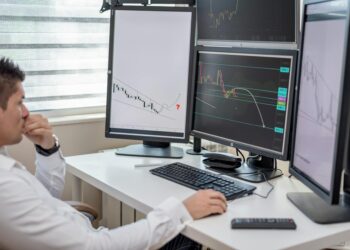 A financial analyst examines stablecoin yield graphs and data on a computer screen.